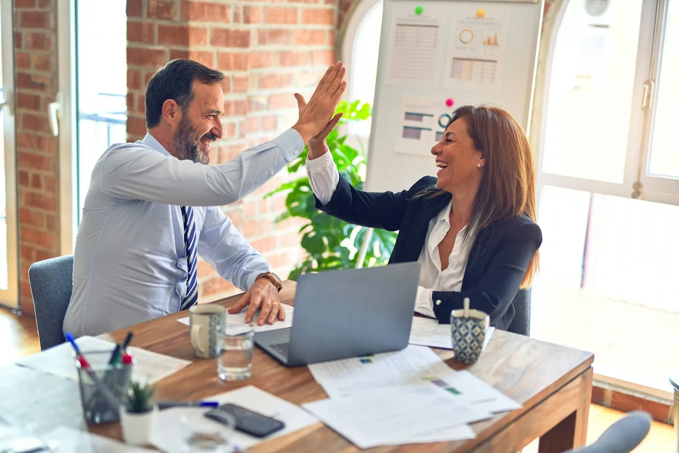 Two colleagues celebrating a campaign plan at a shared desk